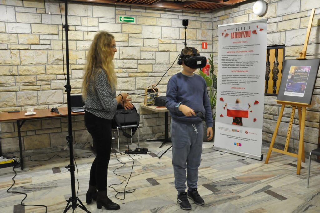 Kobieta w szarej bluzie stoi obok chłopca, który ma założone google VR.