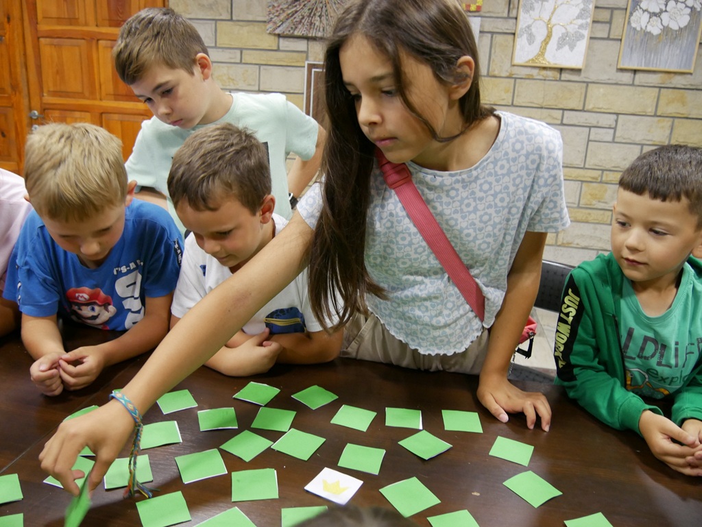 Dzieci stoją przy stole z zielonymi karteczkami.
