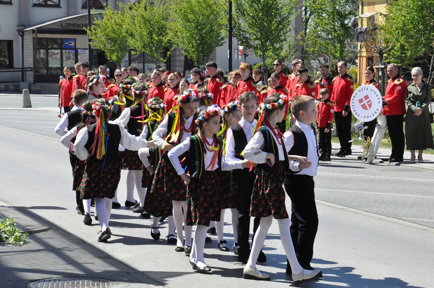 Grupa dzieci tańczy poloneza. Dziewczynki mają wianki we włosach. okolica miejskiego parku.