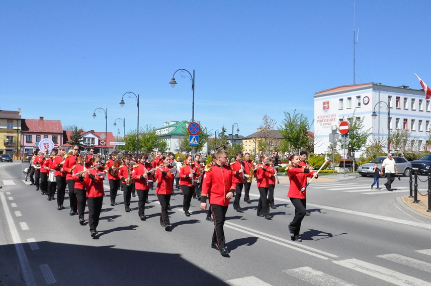 Orkiestra dęta w czerwonych strojach maszeruje ulicami miasta. pogodny dzień.